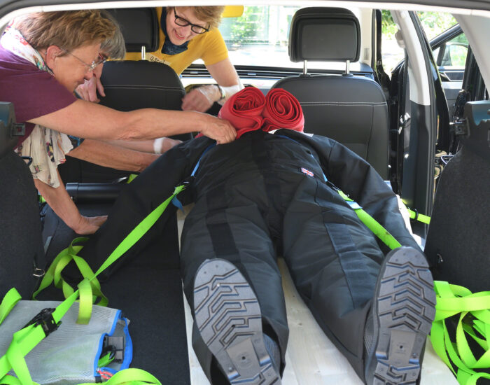 Mehrere Personen üben den behelfsmäßigen Patiententransport mit einer Puppe.