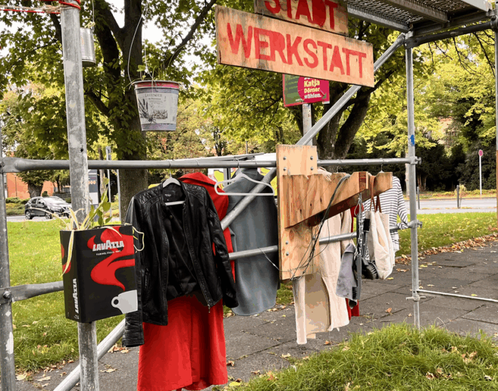 Kleider hängen an einer Stange auf der Stadtbaustelle Chlodwigplatz.