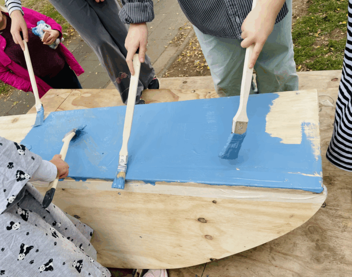 Hände halten Pinsel in der Hand und bemalen Holz blau.